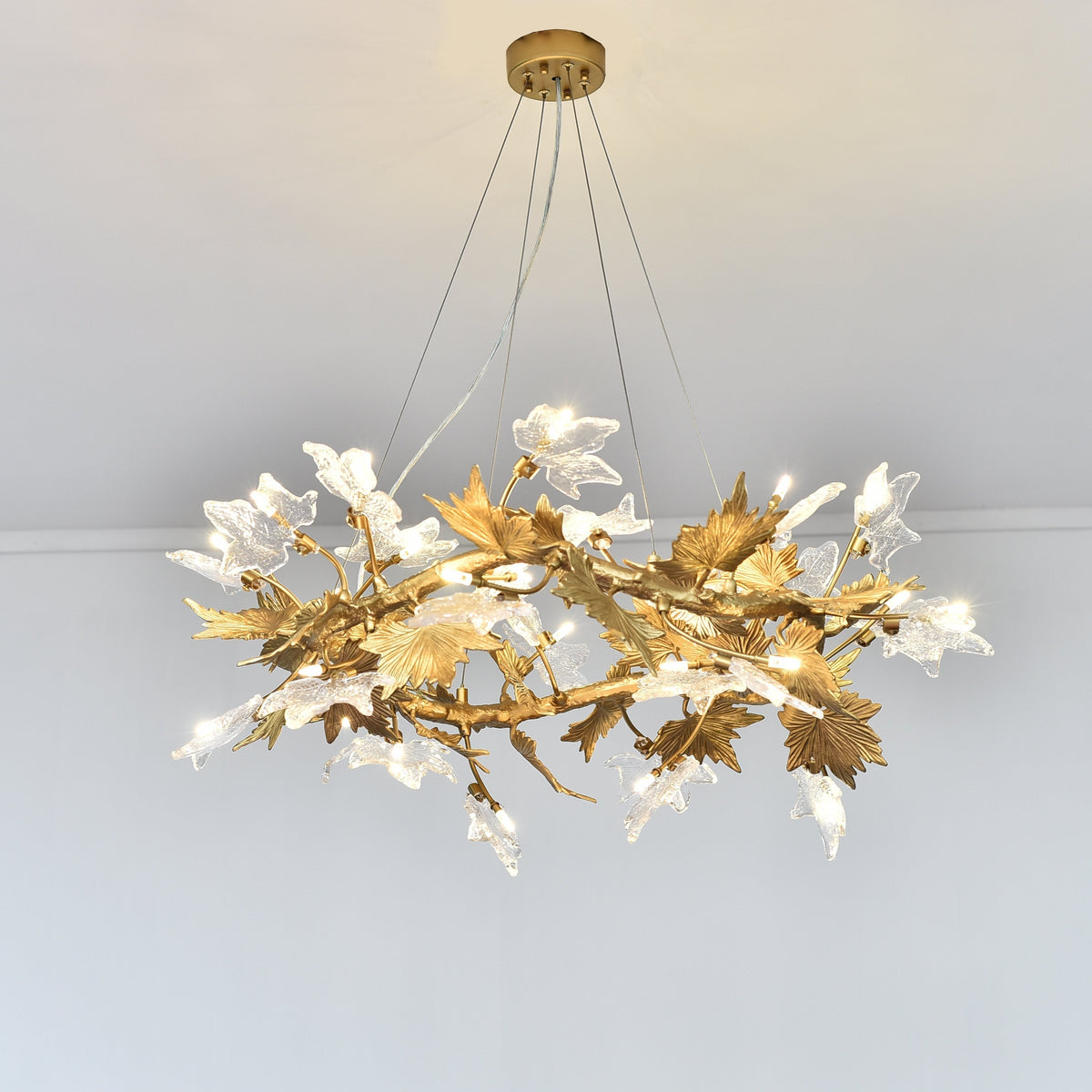 Ion chandelier with pale and metallic leaf-like forms across an open round branch arrangement