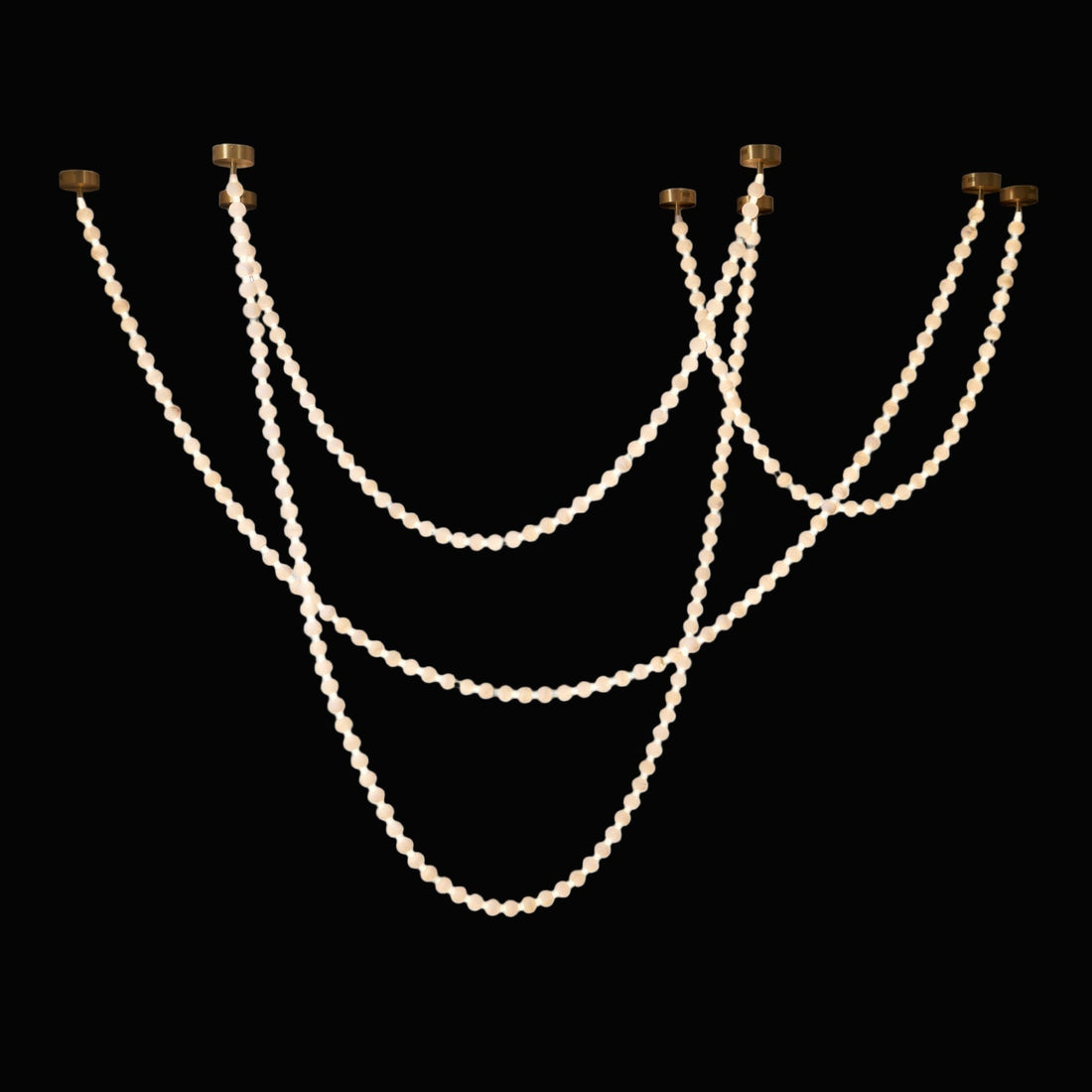 Curving strands of round alabaster elements suspended from ceiling points