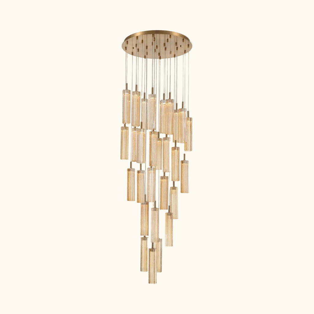 A modern multi-light linear chandelier with a brushed gold circular canopy and multiple hanging clear glass cylinder shades of varying lengths, shown against a plain off-white background.