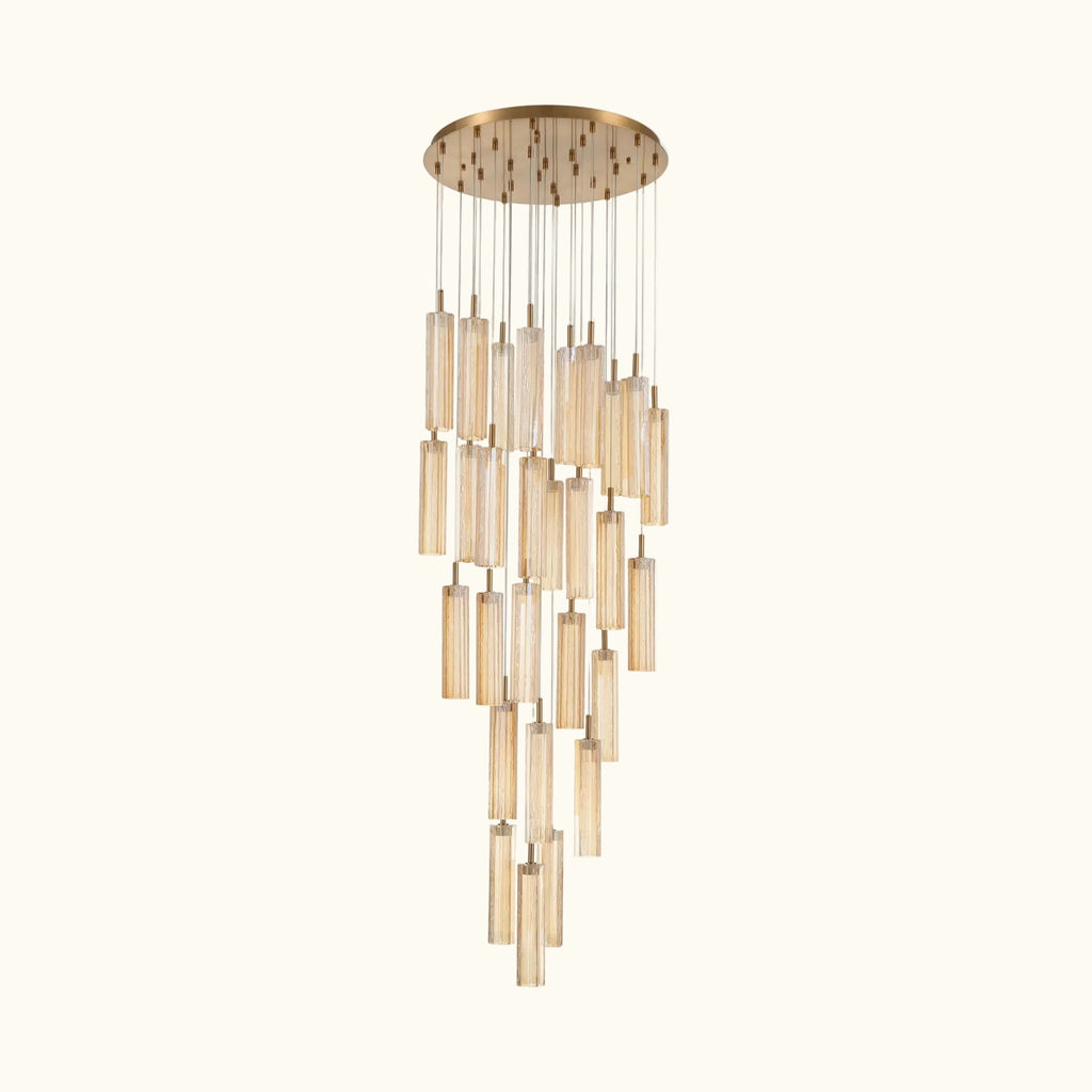 A modern multi-light linear chandelier with a brushed gold circular canopy and multiple clear glass cylinder shades of varying lengths, suspended against a plain white background.