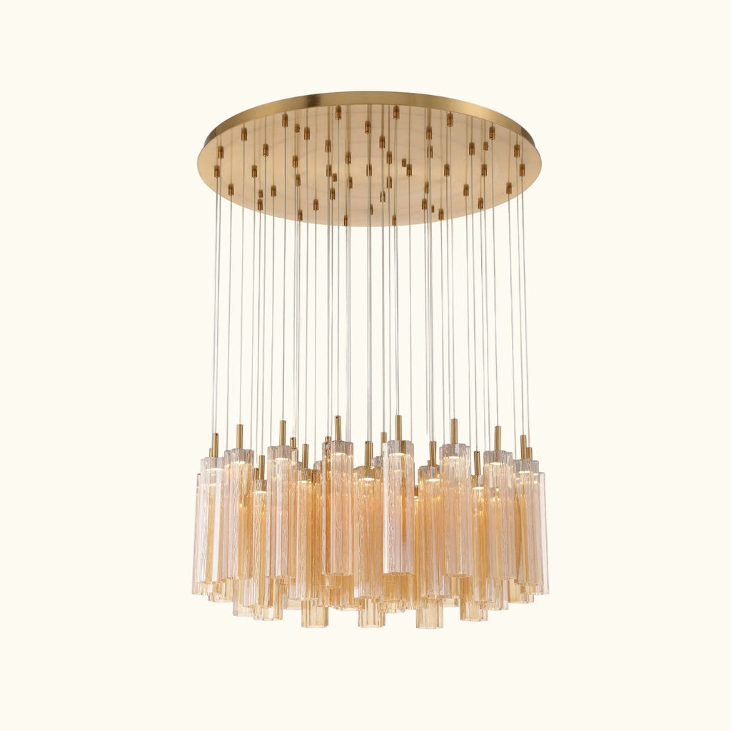 A modern multi-light chandelier with a brushed gold circular canopy, multiple thin suspension rods, and clear cylindrical glass shades, shown against a plain white background.