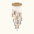 A modern multi-light chandelier with a circular gold-toned ceiling canopy, clear glass tubes, and brushed silver metal accents, suspended against a plain white background.