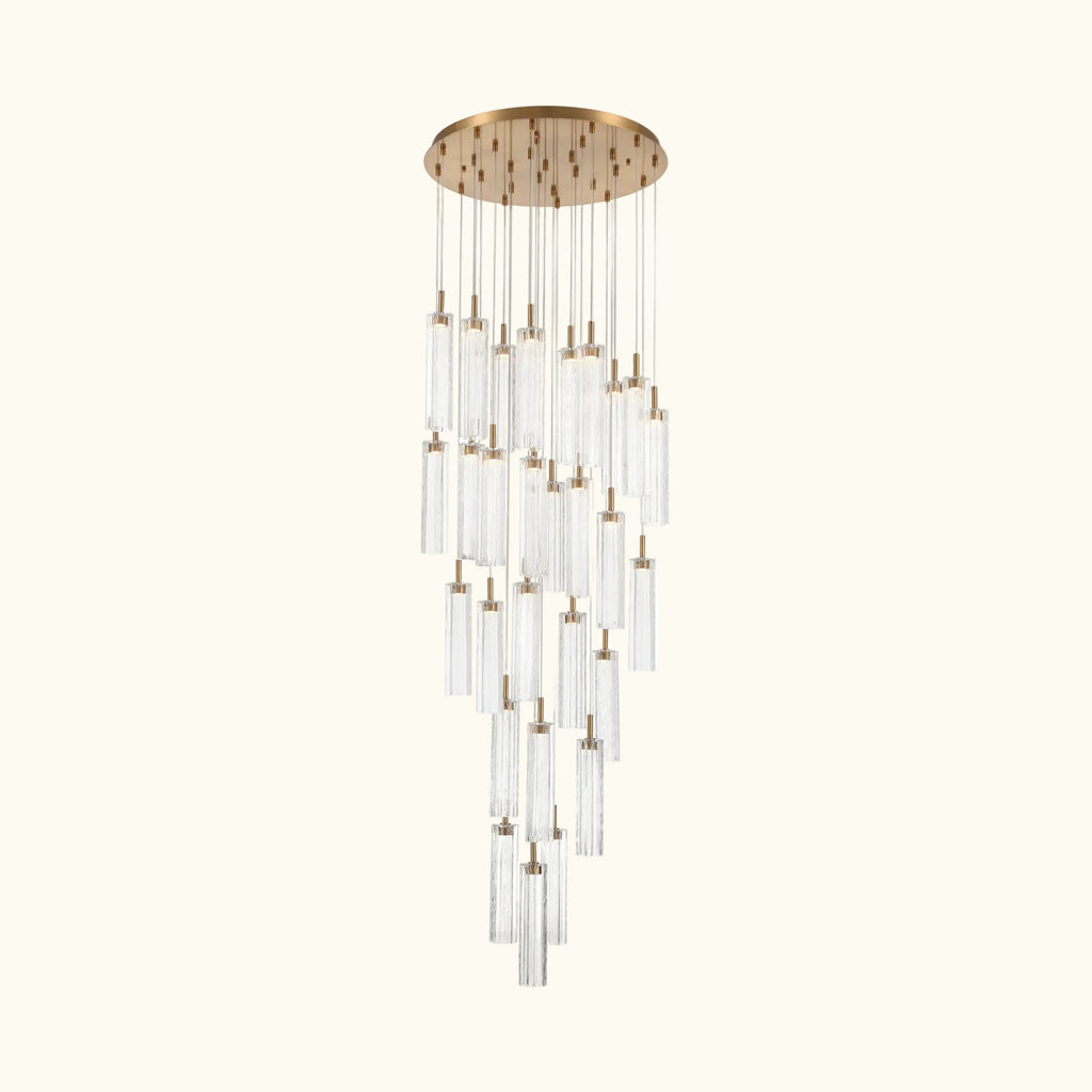 A modern multi-light linear chandelier with a brushed gold circular canopy and multiple clear glass cylindrical tubes of varying lengths, suspended against a plain white background.