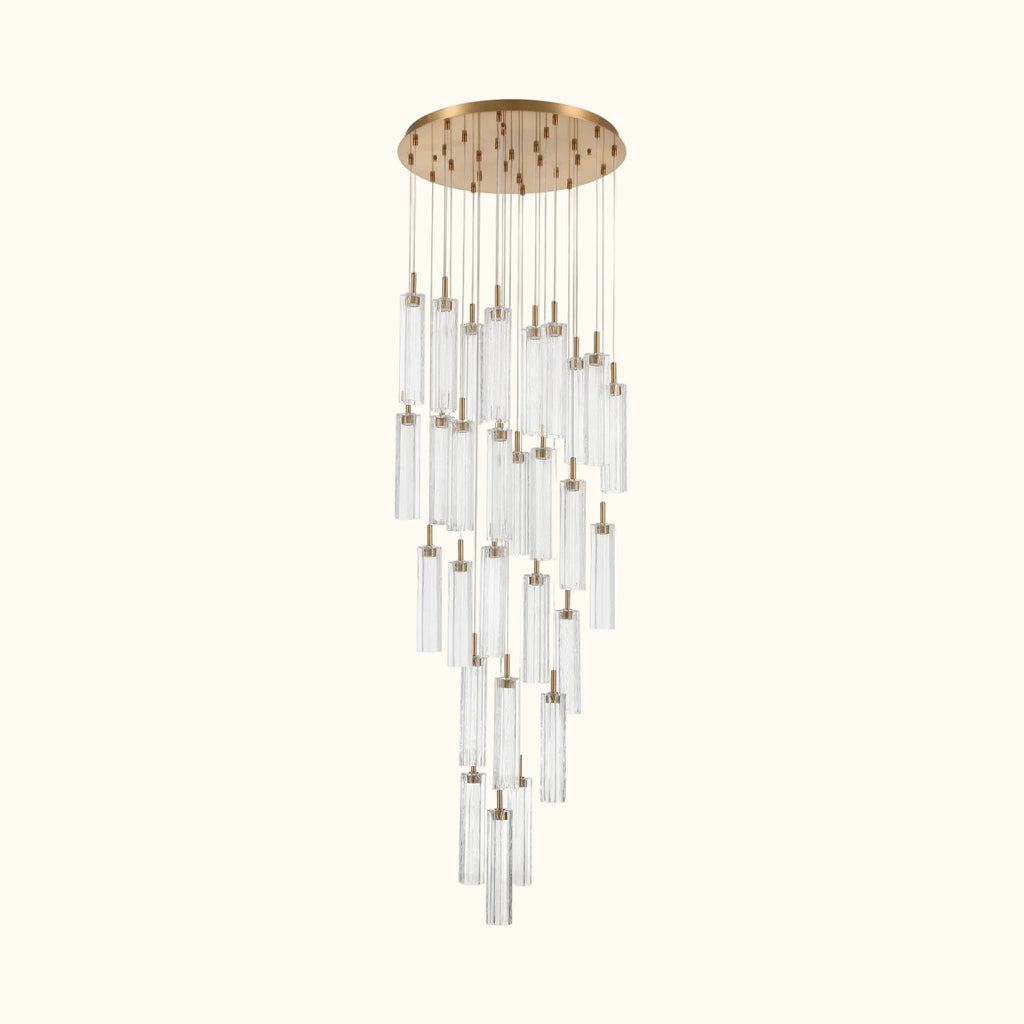 A modern multi-light linear chandelier with a brushed gold circular canopy and multiple clear glass cylinder shades of varying lengths, suspended against a plain white background.