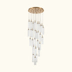 A modern multi-light linear chandelier with a brushed gold circular canopy and multiple clear glass cylinder shades of varying lengths, suspended against a plain white background.