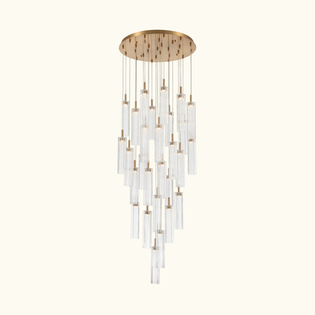 A modern multi-light chandelier with a brushed gold circular ceiling canopy and multiple clear glass cylinder tubes of varying lengths, suspended against a solid white background.