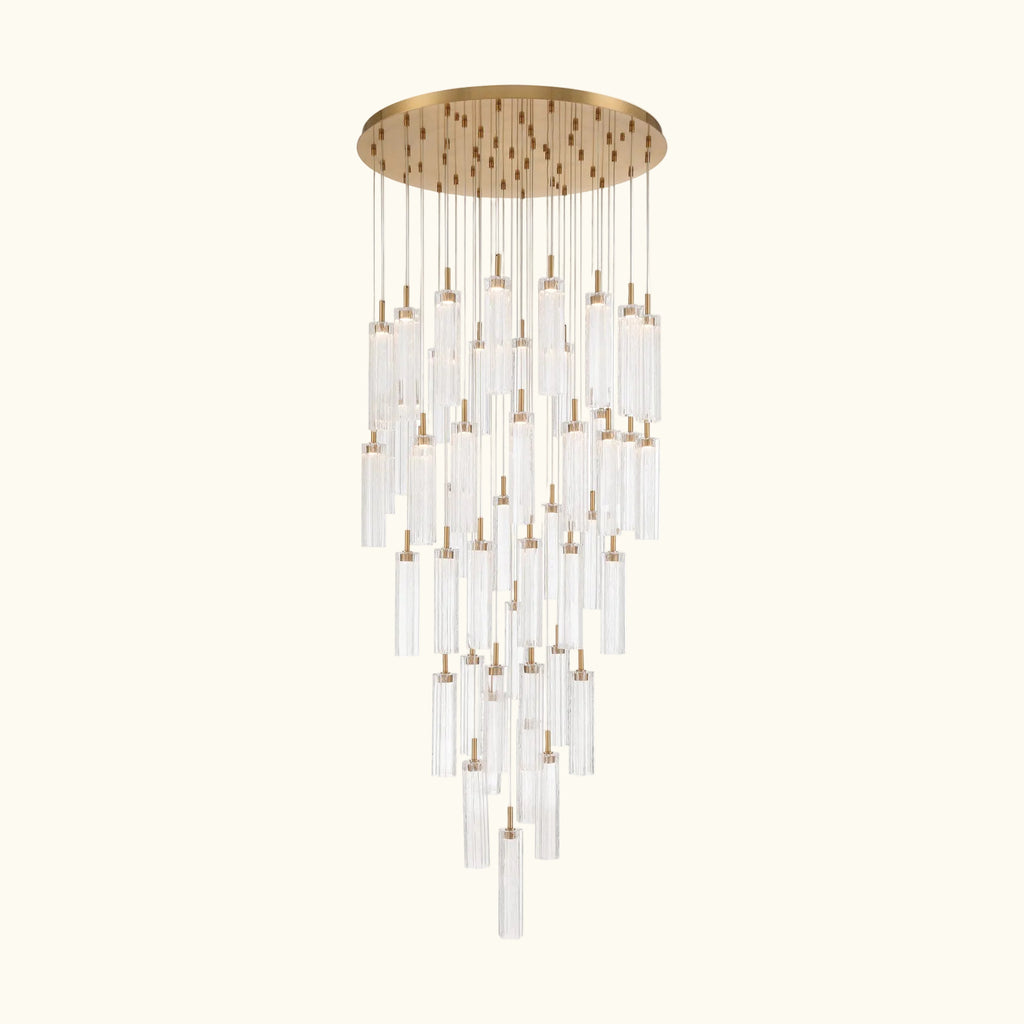 A modern multi-light chandelier with a brushed gold circular canopy and multiple clear glass cylinder tubes of varying lengths, suspended against a solid white background.