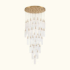A modern multi-light chandelier with a brushed gold circular canopy and multiple clear glass cylinder tubes of varying lengths, suspended against a solid white background.