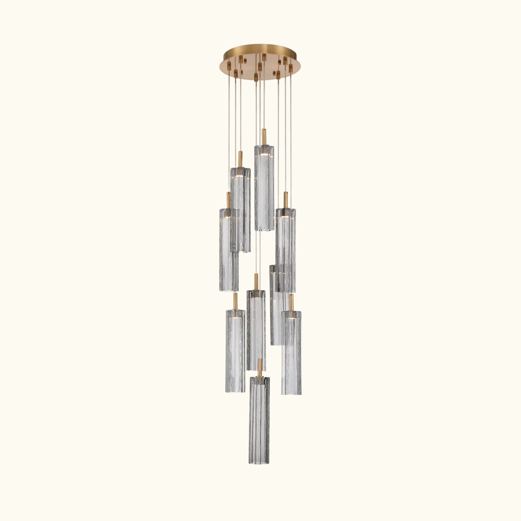 A modern multi-light linear chandelier with six clear ribbed glass cylinders suspended from a round brushed gold ceiling canopy by thin metal rods.