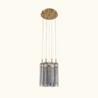 Modern pendant light with gold fixture and clear cylindrical shades on a white background