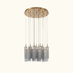 A modern multi-light linear chandelier with a brushed gold circular canopy and multiple clear glass cylinder shades suspended by thin rods, shown against a plain white background.