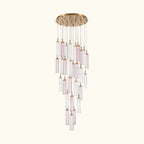 A modern multi-light linear chandelier with a brushed gold circular canopy and multiple clear glass tubes with soft pink tinted sections, suspended against a plain white background.