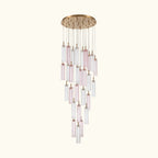 A modern multi-light chandelier with a round gold-toned ceiling canopy, featuring multiple clear glass cylinder shades and several pink-tinted glass tubes suspended at varying lengths against a white background.