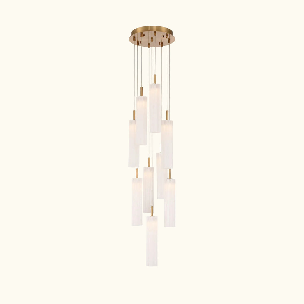 A modern multi-light linear chandelier with a brushed gold ceiling canopy and multiple cylindrical frosted glass shades of varying lengths, suspended against a solid white background.