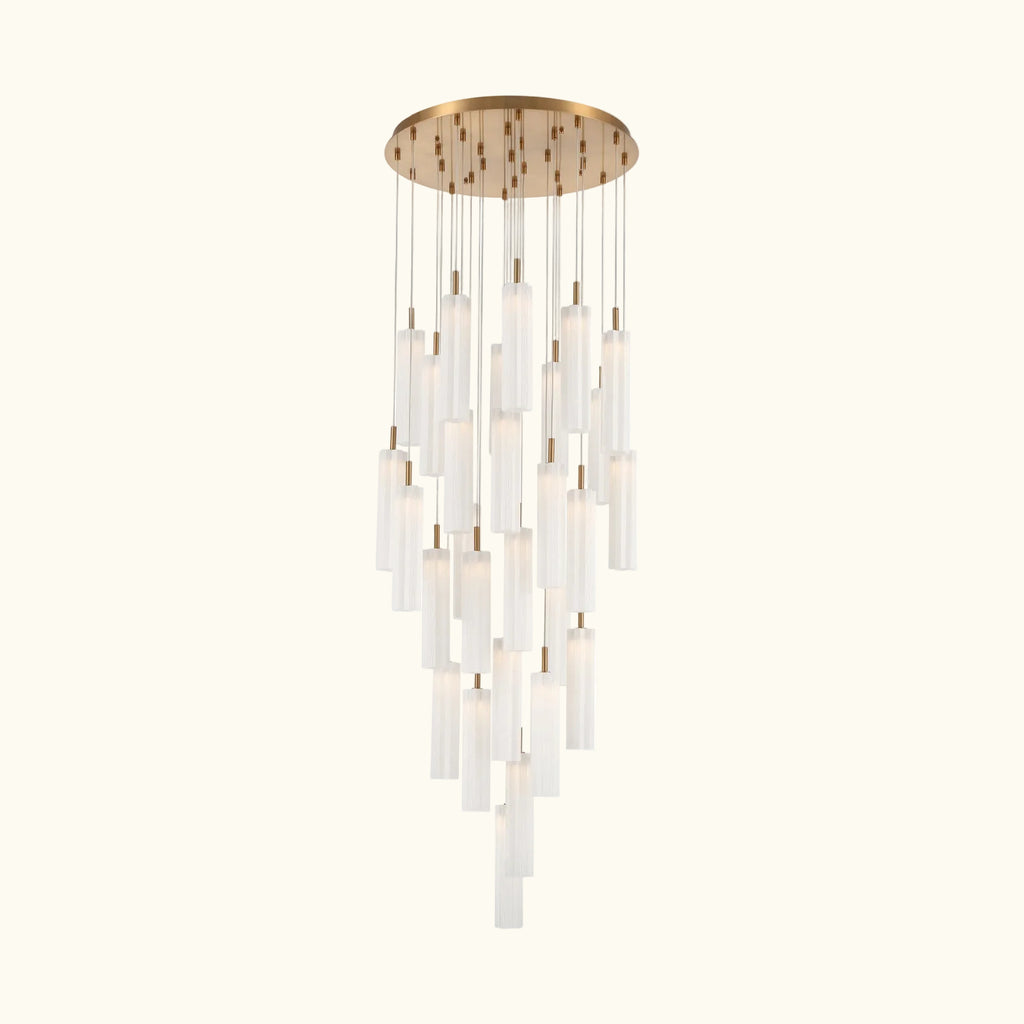 A modern multi-light chandelier with a circular brushed gold ceiling canopy, multiple hanging clear glass cylindrical shades of varying lengths, and warm white light emission, shown against a plain white background.
