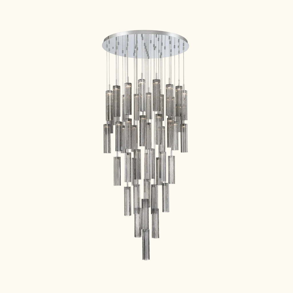 A modern multi-light chandelier with a circular silver canopy and multiple tiers of hanging cylindrical glass shades in brushed silver and smoked gray, shown against a plain white background.