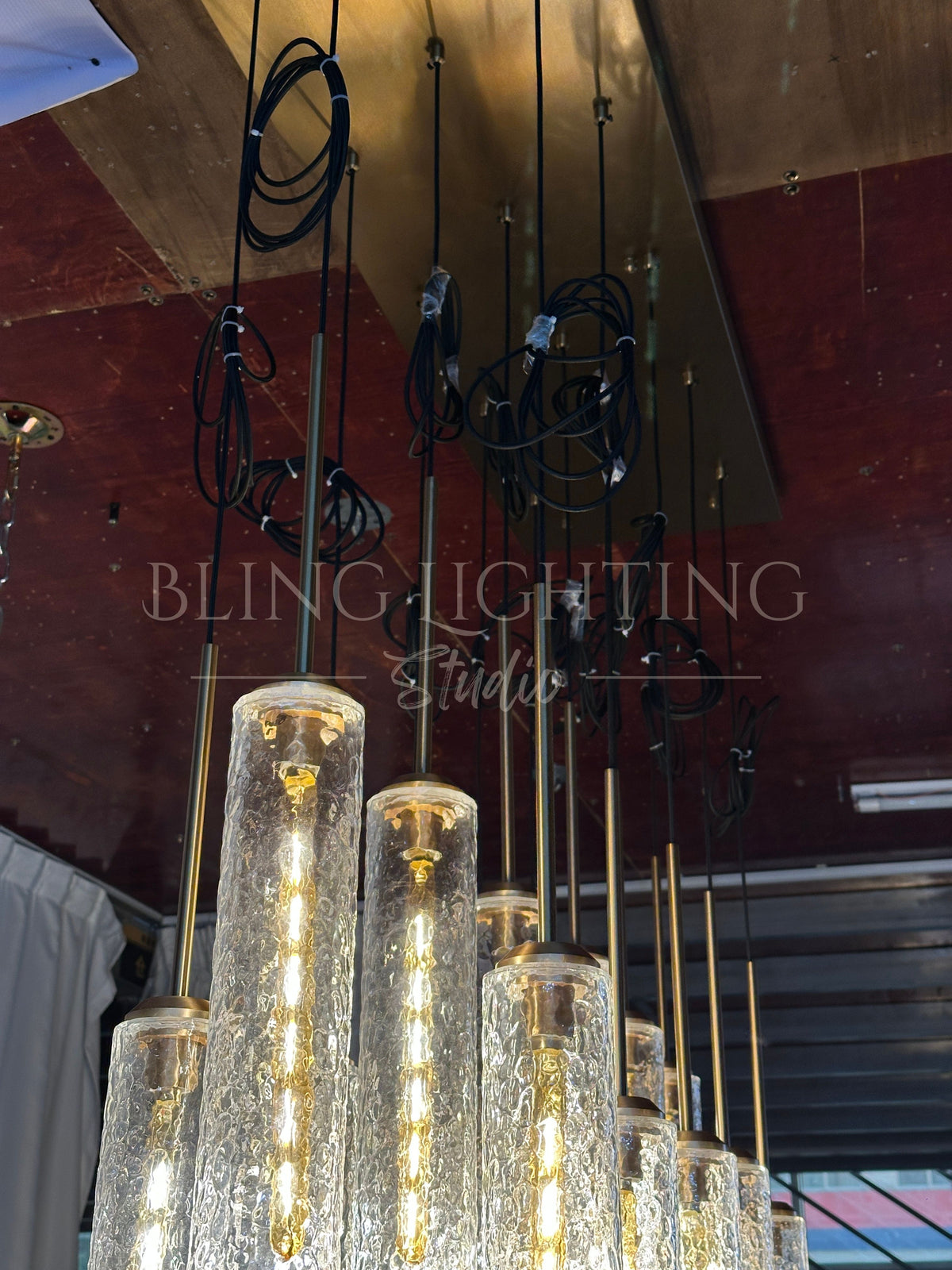 End view of the Colleena linear chandelier showing long rods and clustered hammered glass cylinders