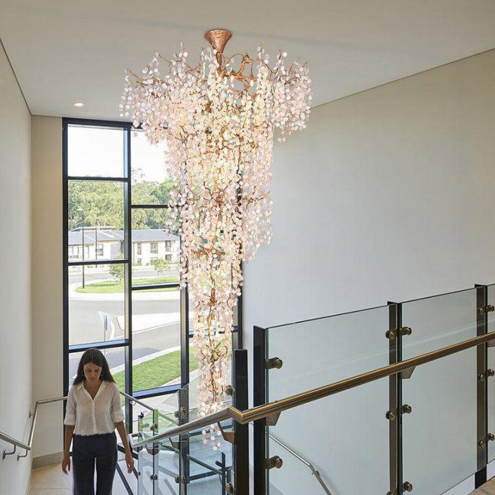 Double-height staircase with a cascading crystal branch chandelier