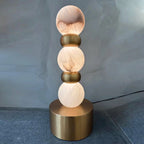 Pearl Xyx Alabaster Table Lamp — product setting and fixture profile, three rounded stone forms above a metal base (view 2)