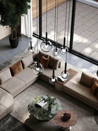 Cleo Bubble Glass Chandelier suspended in a high ceiling living room with glass wall