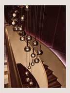 Cleo Bubble Glass Staircase Chandelier installed in a spiral staircase with smoke glass globes