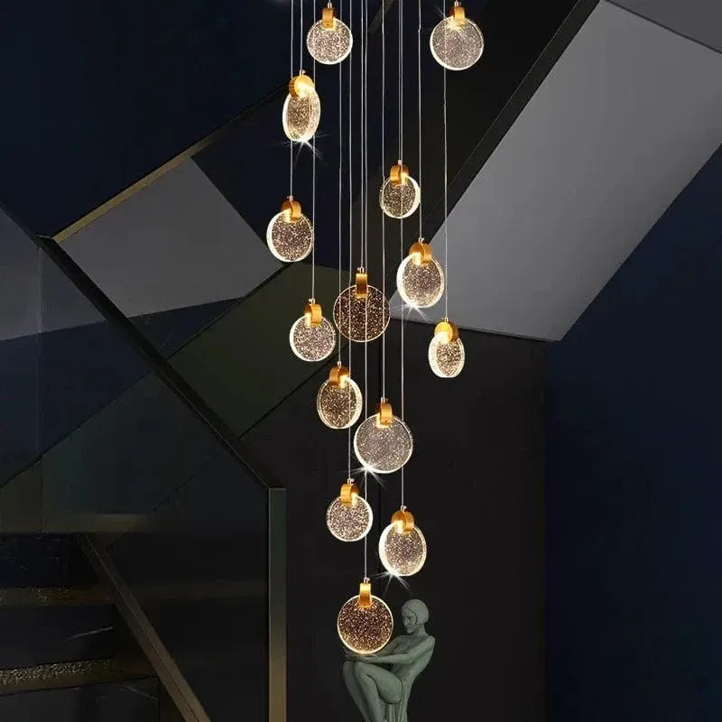Contemporary LED Chandelier with Crystal Pendant glowing in a dark stairwell with cascading crystal discs and sculpture decor