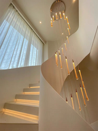 Crystal Raindrop Cascade Chandelier with gold round canopy and staggered illuminated crystal drops in a high ceiling stairwell