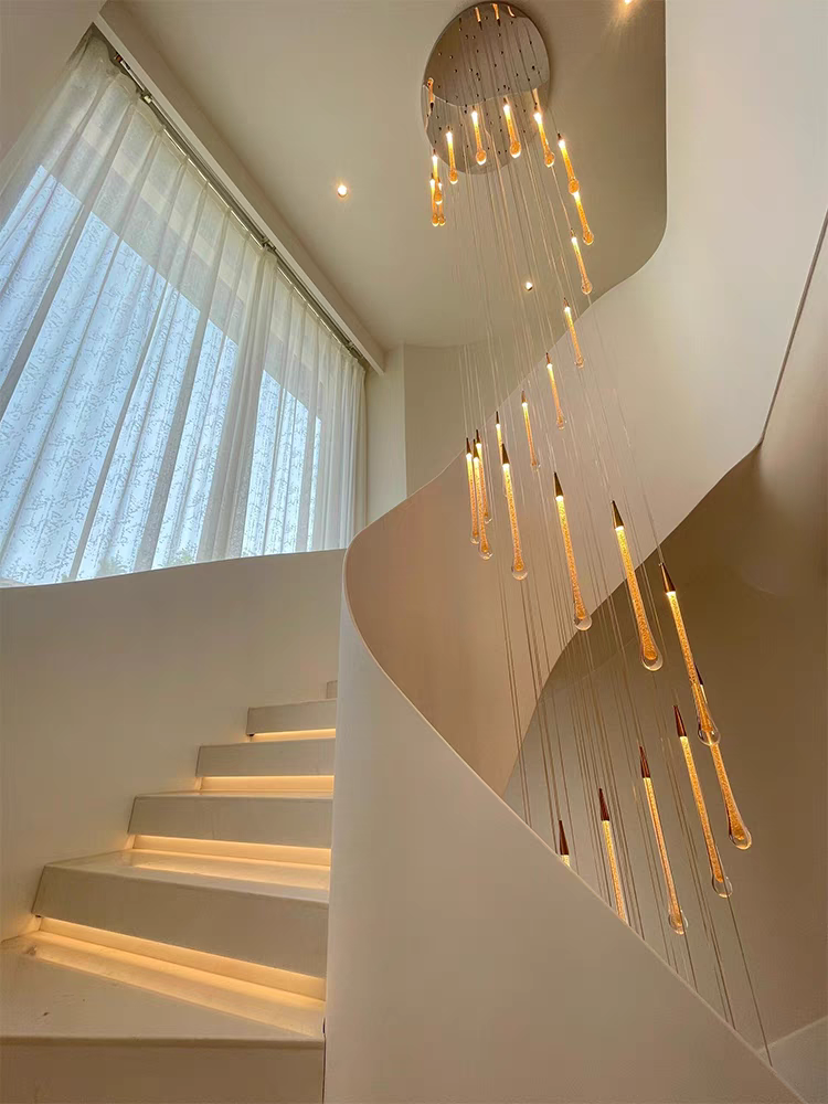 Crystal Raindrop Cascade Chandelier with gold round canopy and staggered illuminated crystal drops in a high ceiling stairwell