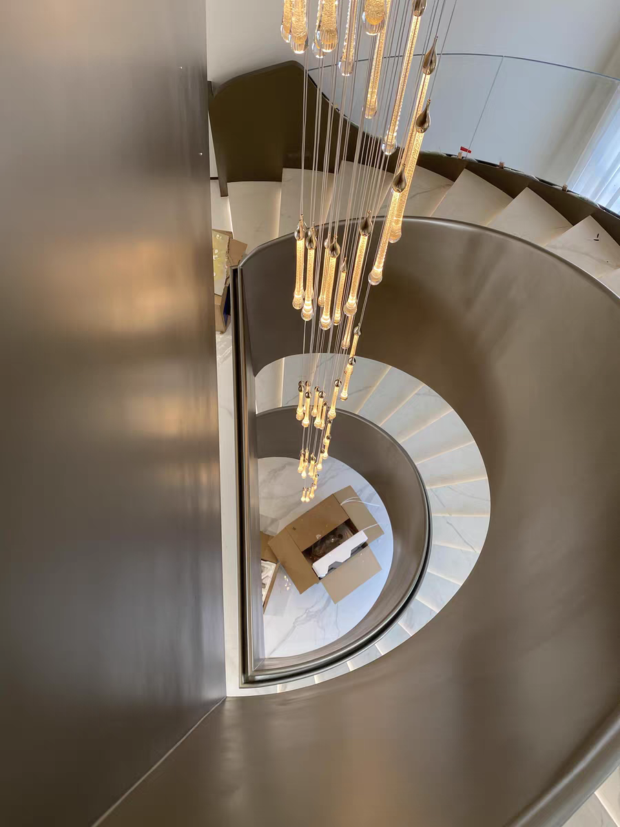 Top view of Crystal Raindrop Cascade Chandelier hanging through a curved multi-story staircase void