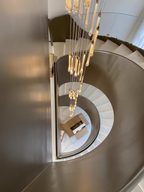 Top view of Crystal Raindrop Cascade Chandelier hanging through a curved multi-story staircase void