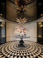 Dandelion multi-tier chandelier over a round floral table in a hotel lobby