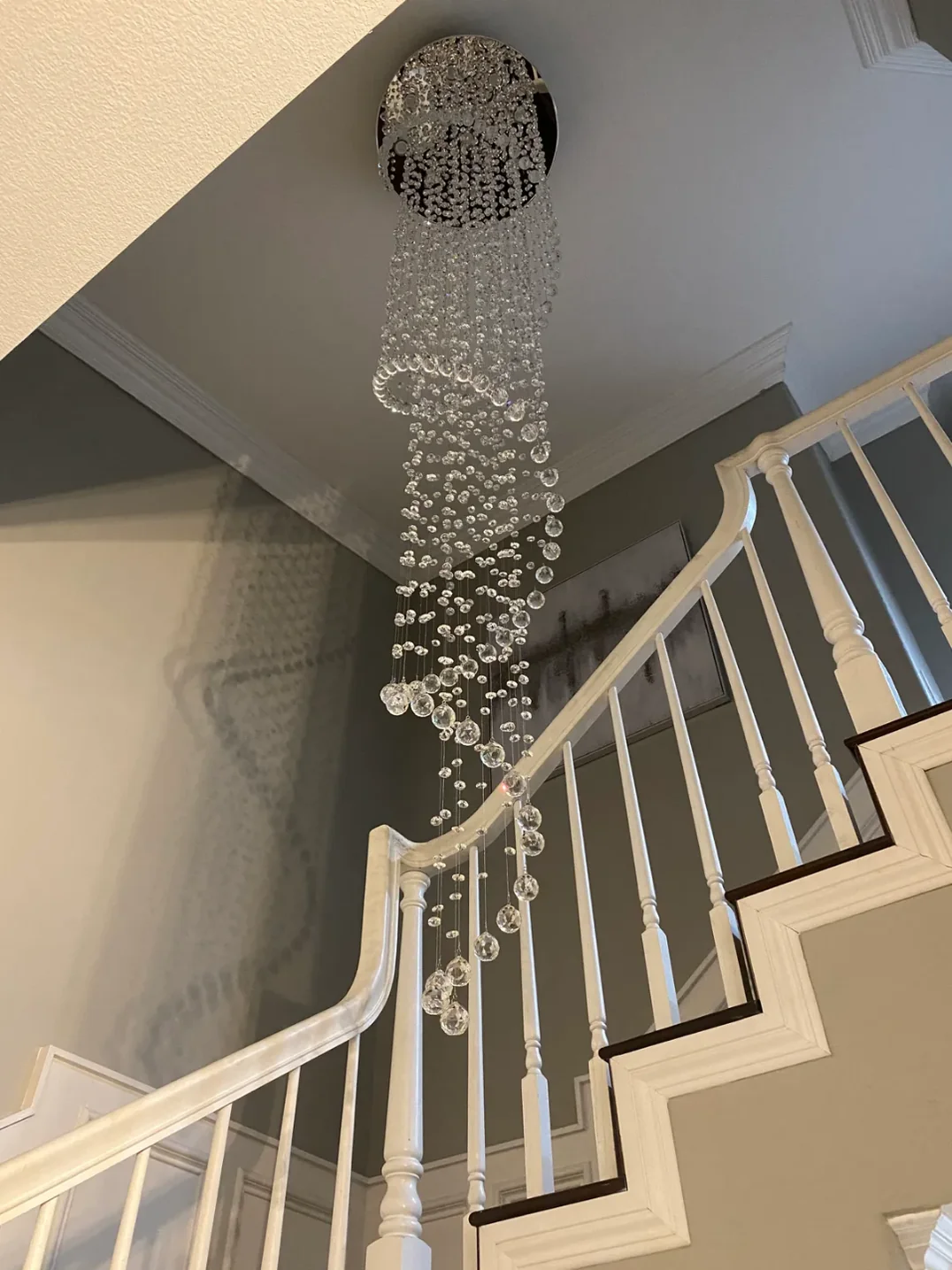 Large Foyer Lighting spiral raindrop crystal chandelier hanging beside a staircase landing