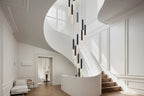 Lum Modern Black Foyer Chandelier For High Ceiling installed beside a white curved staircase with black and white LED tubes