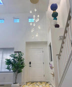 Modern Crystal Chandelier for High Ceiling Living Room installed in a bright foyer beside a staircase