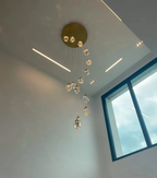 Modern Crystal Chandelier for High Ceiling Living Room hanging from a gold canopy in a tall entryway