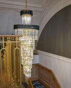 Olivia Crystal Modern Stair Chandelier installed beside a curved staircase with gold railing