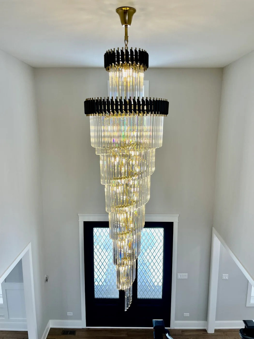 Olivia Crystal Modern Stair Chandelier installed in an entryway stairwell above double doors