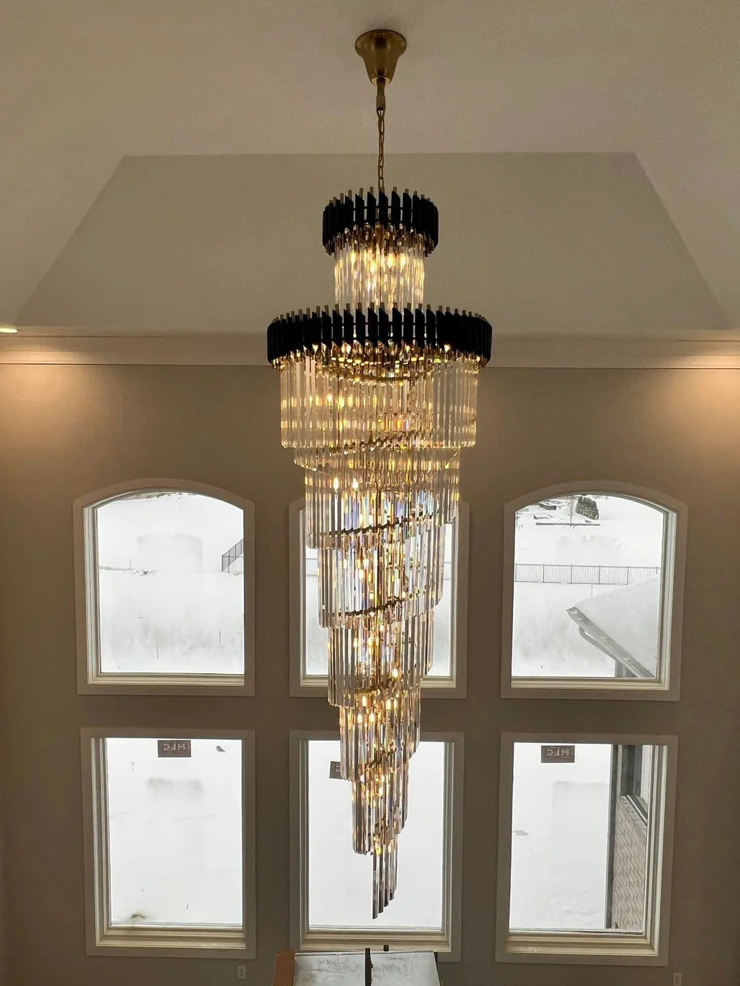 Olivia Crystal Modern Stair Chandelier installed in a foyer with arched windows and a high ceiling