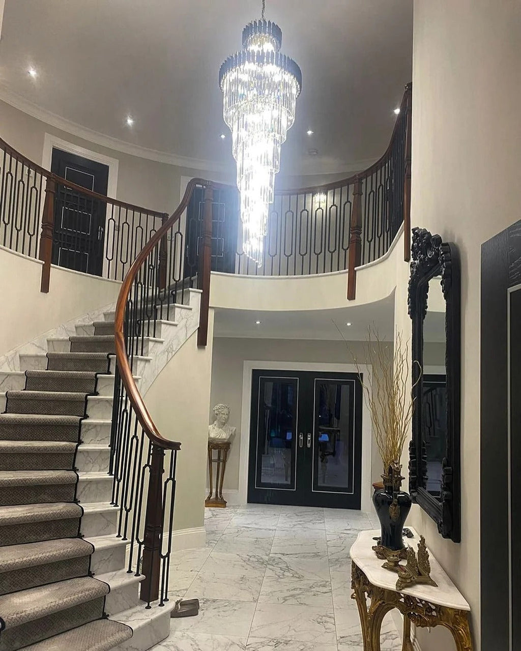 Olivia Crystal Modern Stair Chandelier illuminating a grand staircase entryway with high ceiling