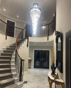 Olivia Crystal Modern Stair Chandelier illuminating a grand staircase entryway with high ceiling