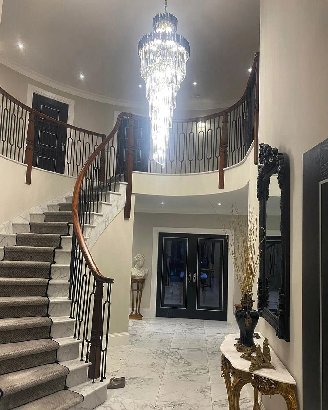 Olivia Crystal Modern Stair Chandelier illuminating a grand staircase entryway with high ceiling