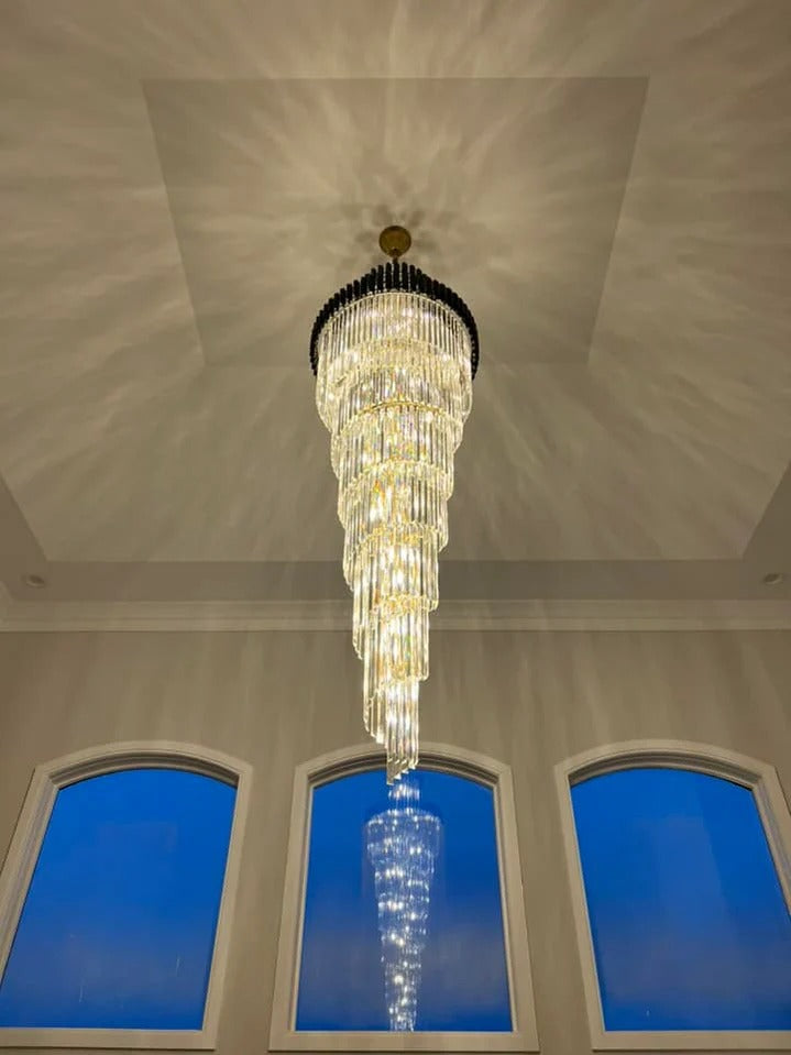 Olivia Crystal Modern Stair Chandelier suspended in a tall foyer with blue arched windows