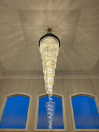 Olivia Crystal Modern Stair Chandelier suspended in a tall foyer with blue arched windows
