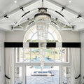 Olivia Crystal Modern Stair Chandelier installed in a bright white foyer entry with arched windows