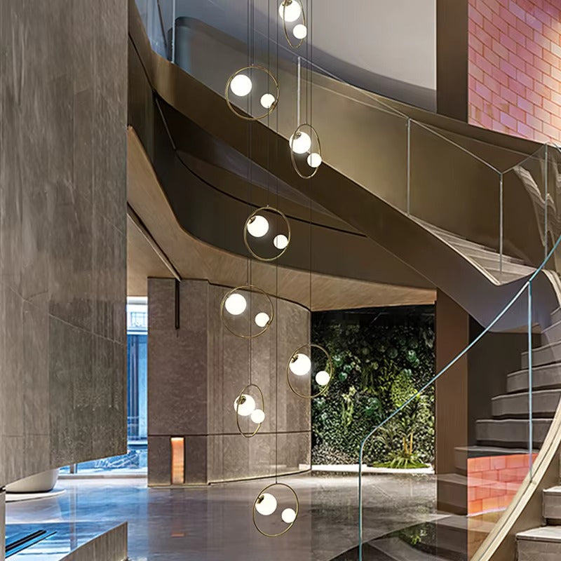 Postmodern Ring Pendant Light for Staircase installed beside a curved stairway with glowing globe lights