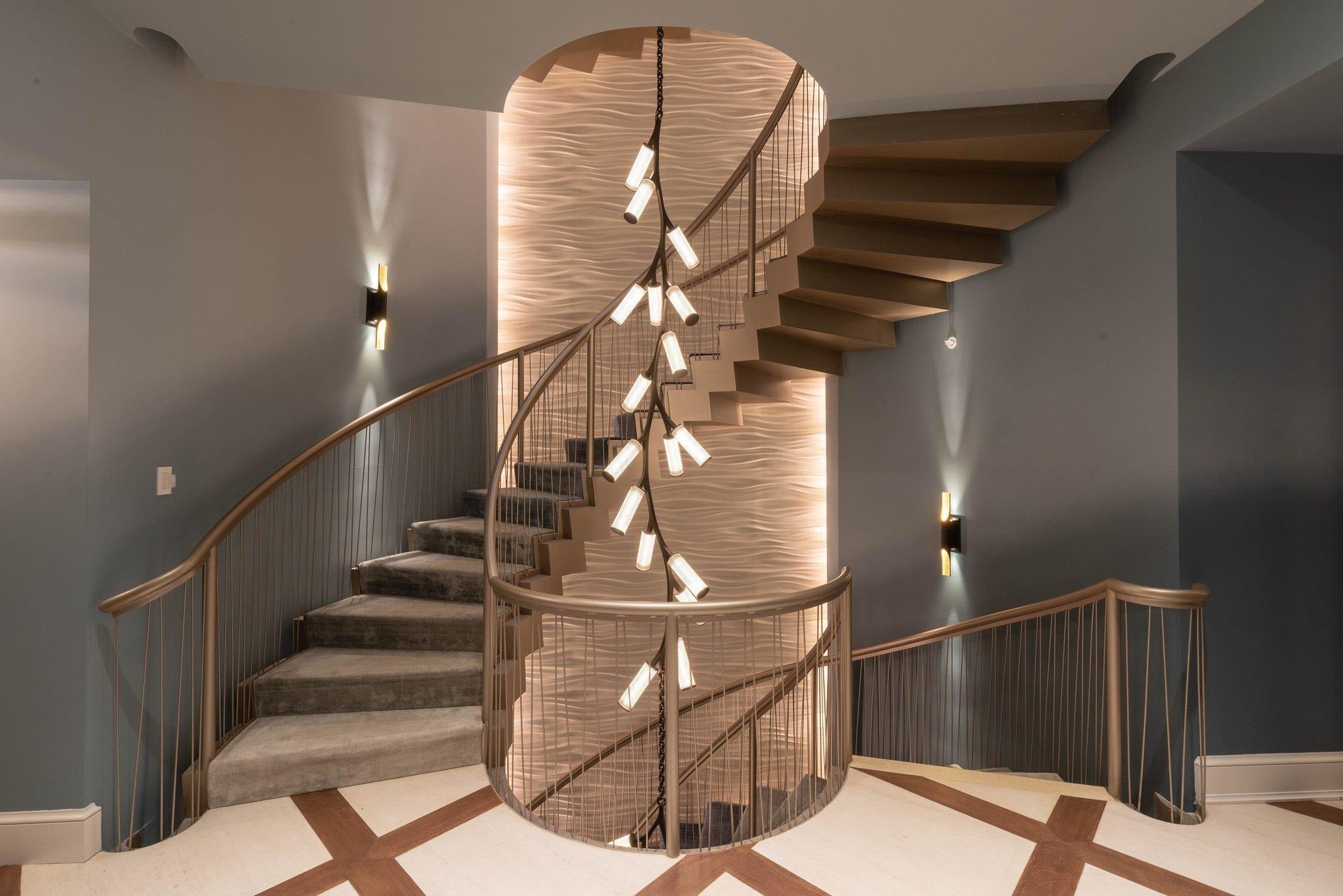 Rhea Modern Simple Staircase Chandelier installed in a curved staircase with warm wall lighting