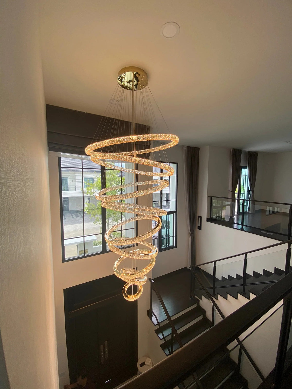 6 Tier Crystal Ring Chandelier for High Ceiling gold finish installed above a stairwell railing