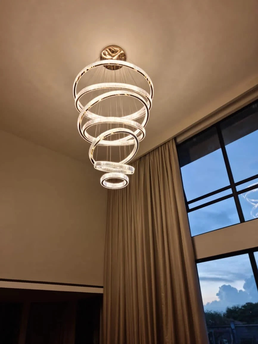 6 Tier Crystal Ring Chandelier for High Ceiling in gold finish hanging near a window corner