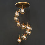 Tenza Modern Staircase Chandelier close view of amber glass spiral ball pendants with gold hardware