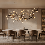 Wanos Ceramic Flower Branch Chandelier installed over a long dining table in a luxury warm neutral dining room with marble wall panels and built-in display shelves.
